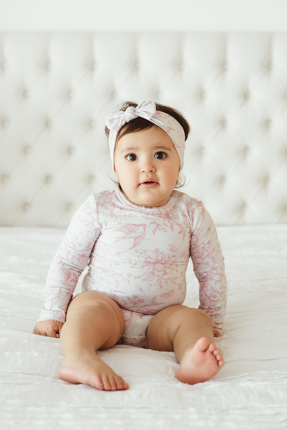 Front view of toddler girl in nature-inspired Botanical Lullaby bamboo bodysuit, showcasing whimsical print with hummingbirds, florals, and vintage garden charm — eco-friendly and gentle on sensitive skin.