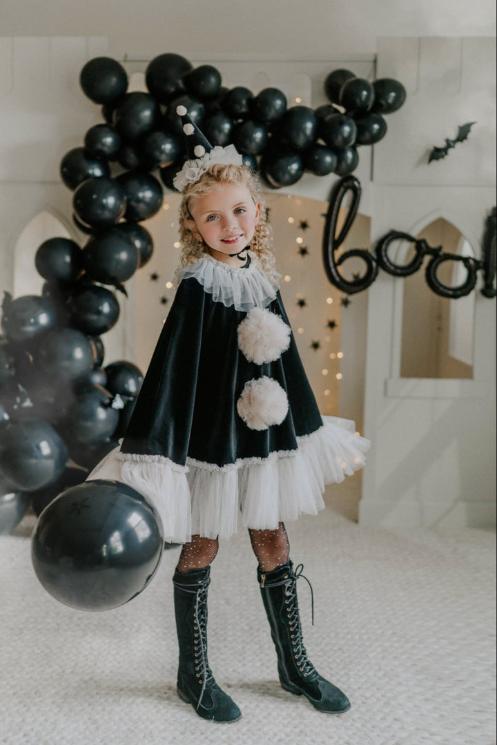 Black velvet pirouette clown cape with ivory tulle ruffle trim hanging on vintage wardrobe