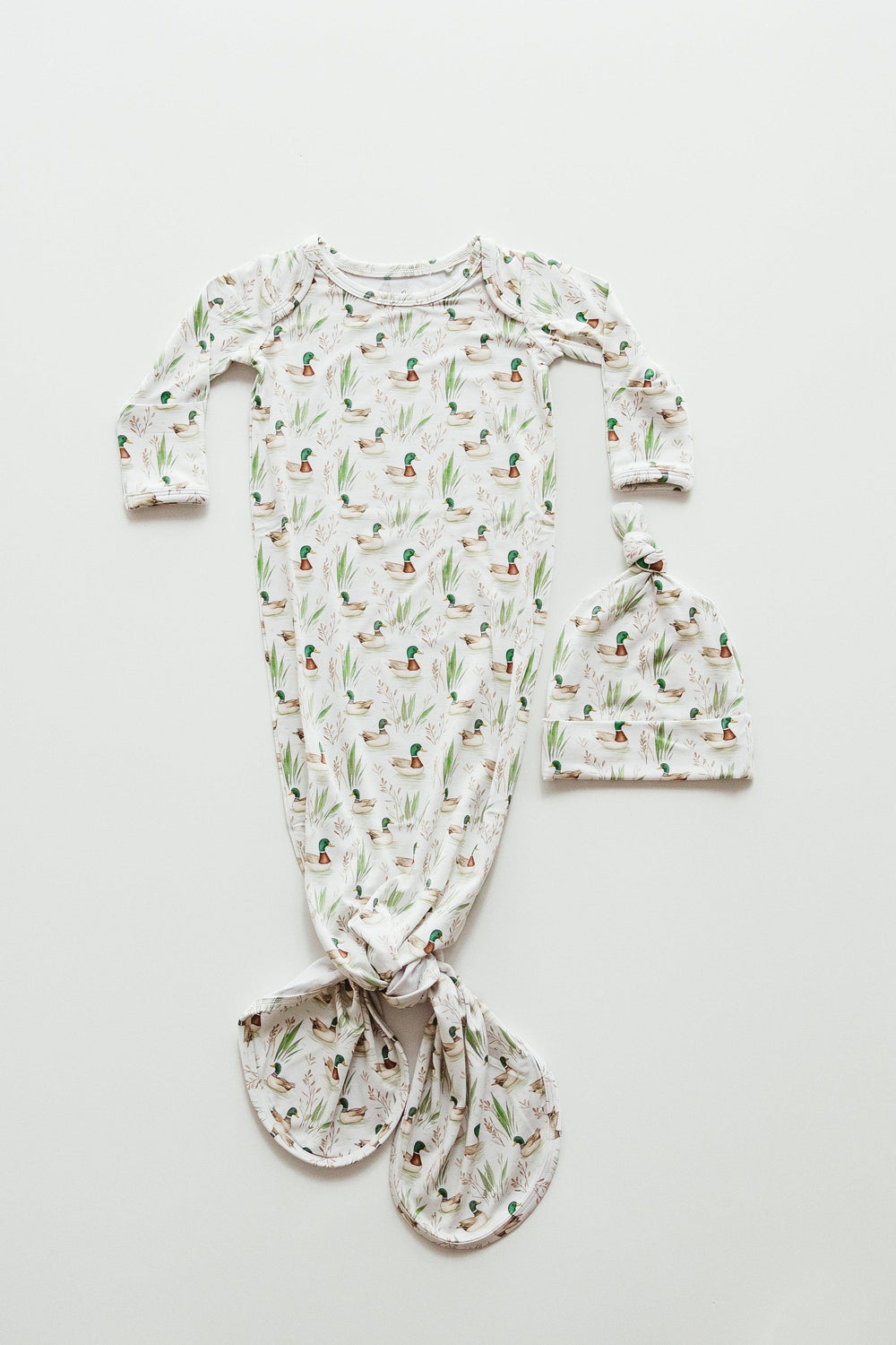 Flat lay of Mallard Ducks bamboo newborn knotted gown featuring a cream background with green-headed ducks swimming through marsh grass — made from ultra-soft, breathable bamboo viscose, perfect for cozy newborn sleep and gifting.