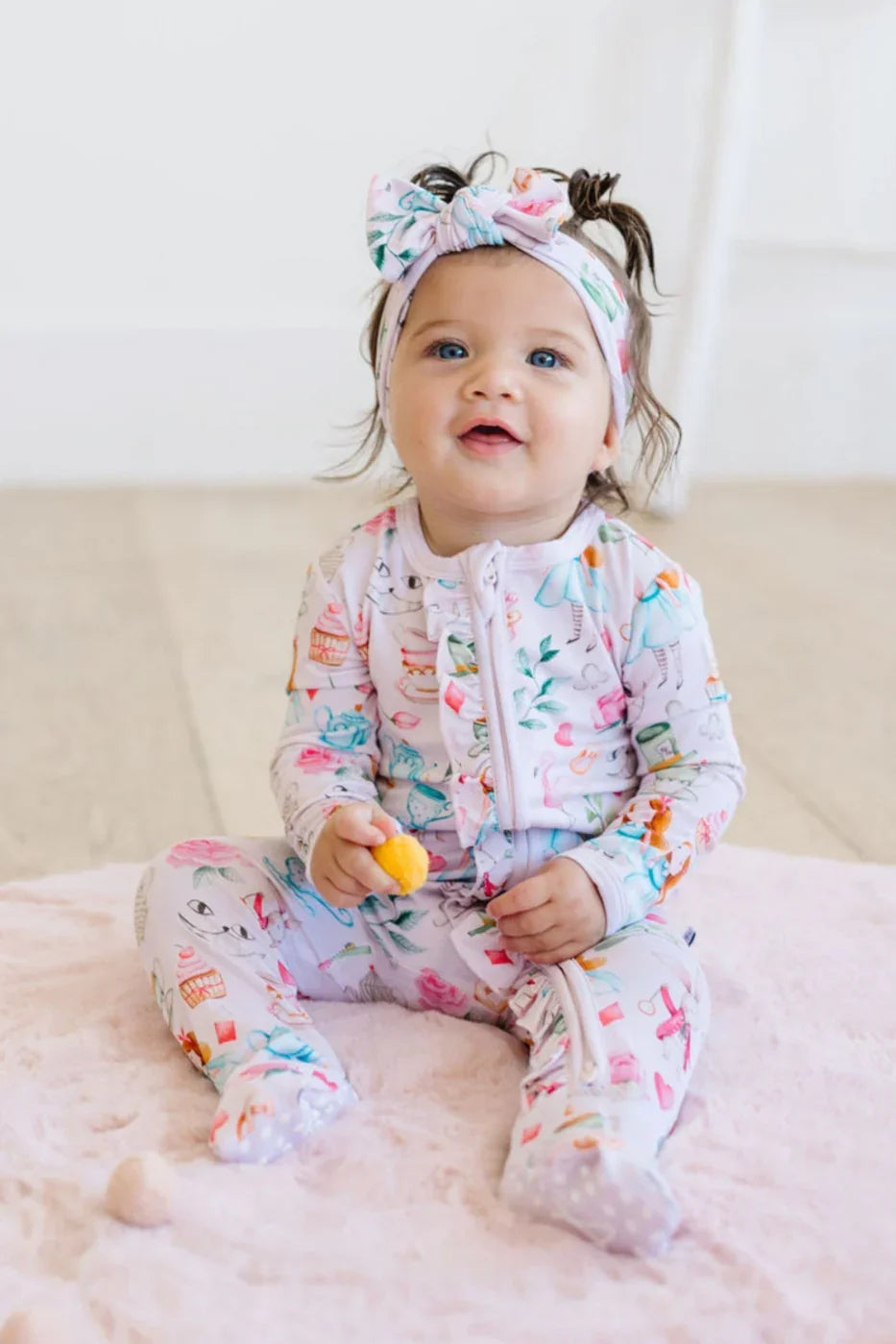 Baby sitting in Adventures with Alice long sleeve bamboo zipper pajamas with convertible feet and dual zipper.