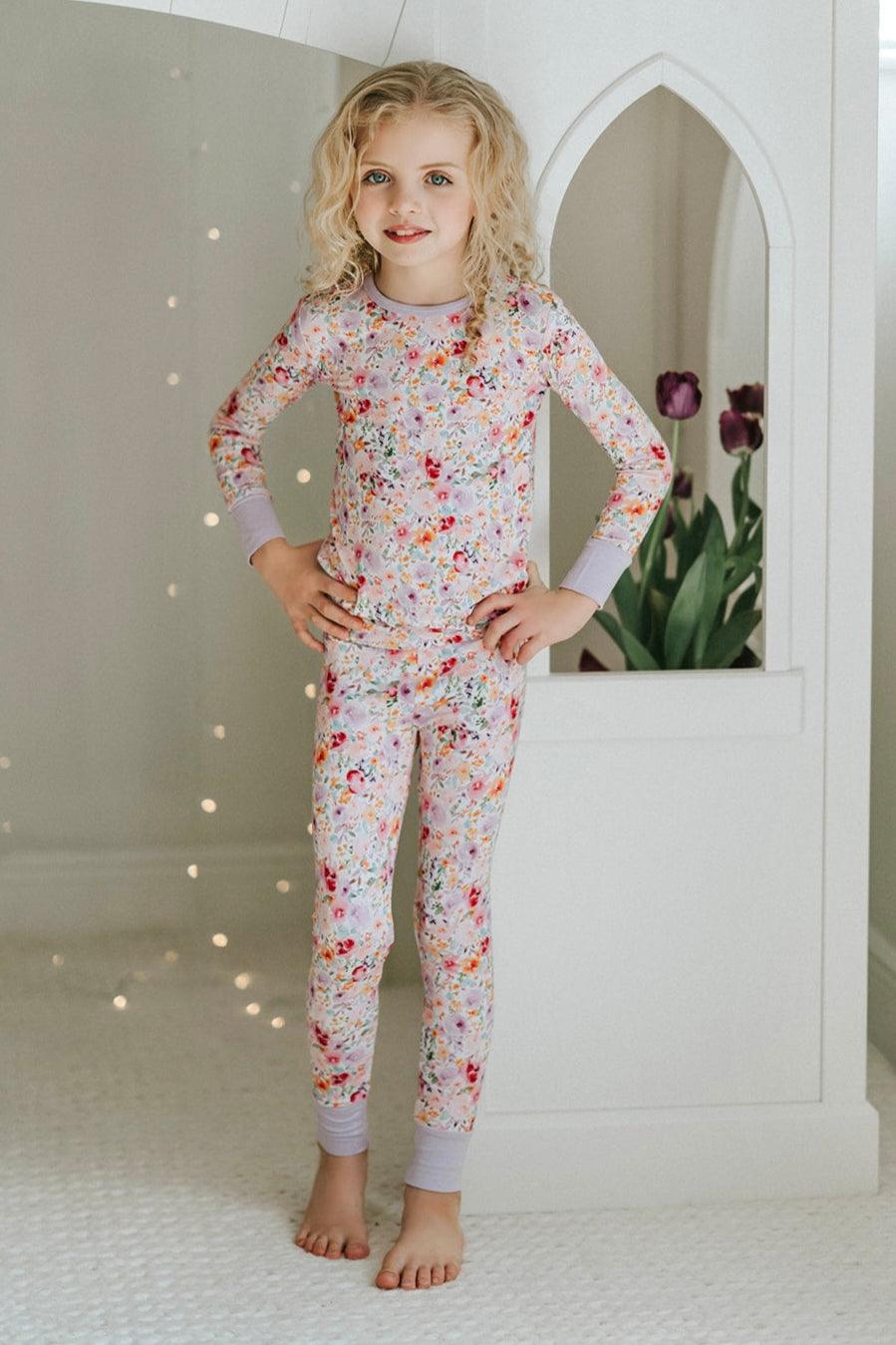 Girl wearing flower garden two-piece bamboo pajamas with long sleeves and floral print pants, front-facing pose.