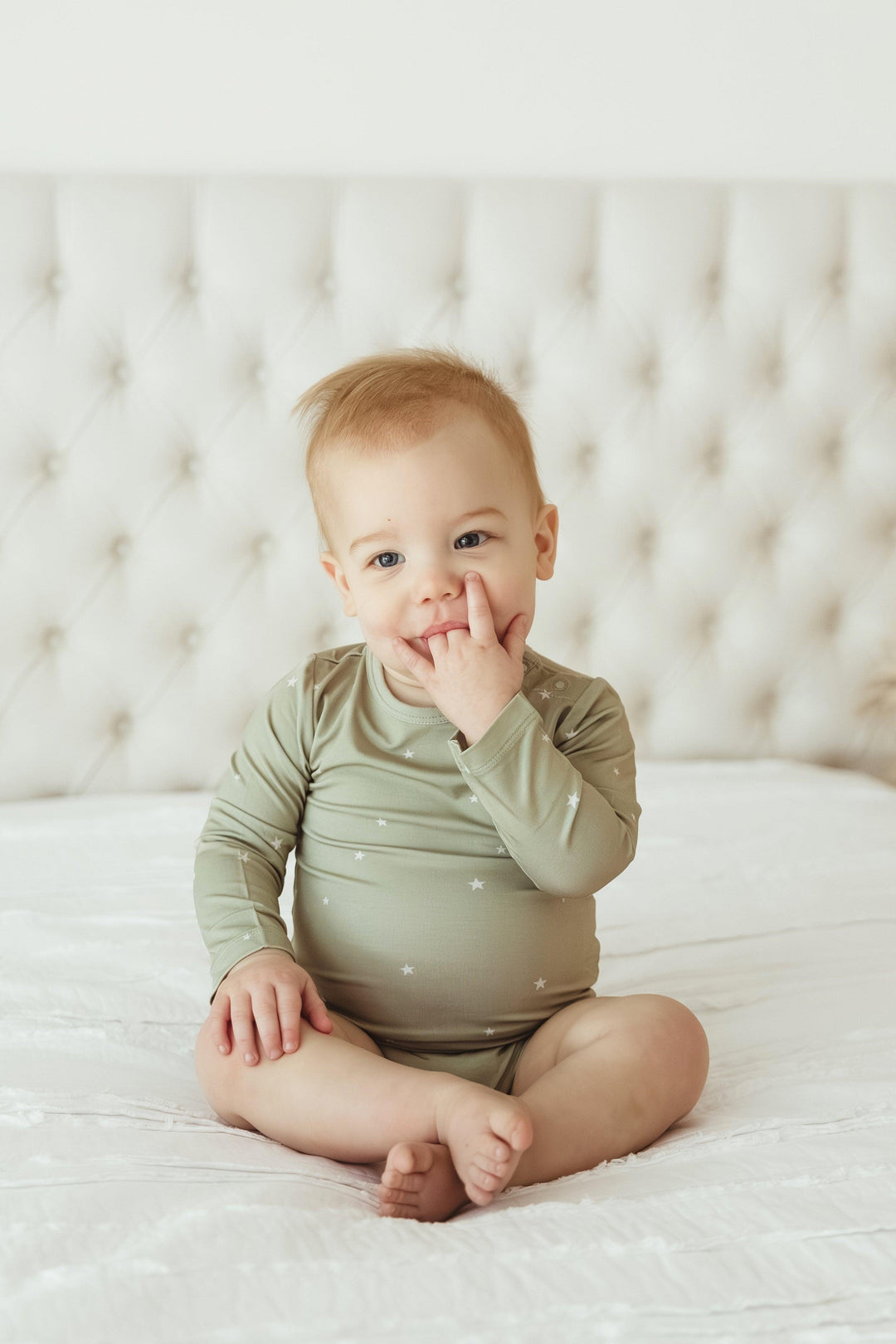 Baby sitting and smiling in sage stars bamboo long sleeve bodysuit with snap closure — soft, gender-neutral outfit for lounging or playtime.