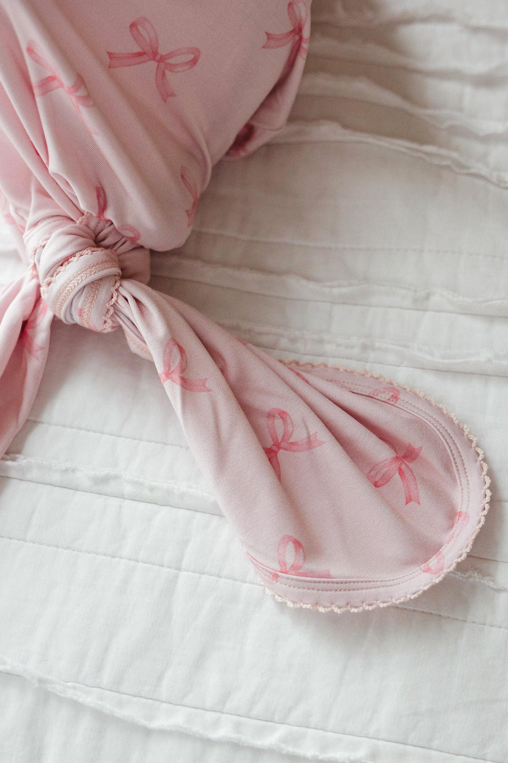 Detailed view of the knotted bottom on bamboo baby gown in pink bows print, showing the adjustable knot and stretch for easy diaper changes.