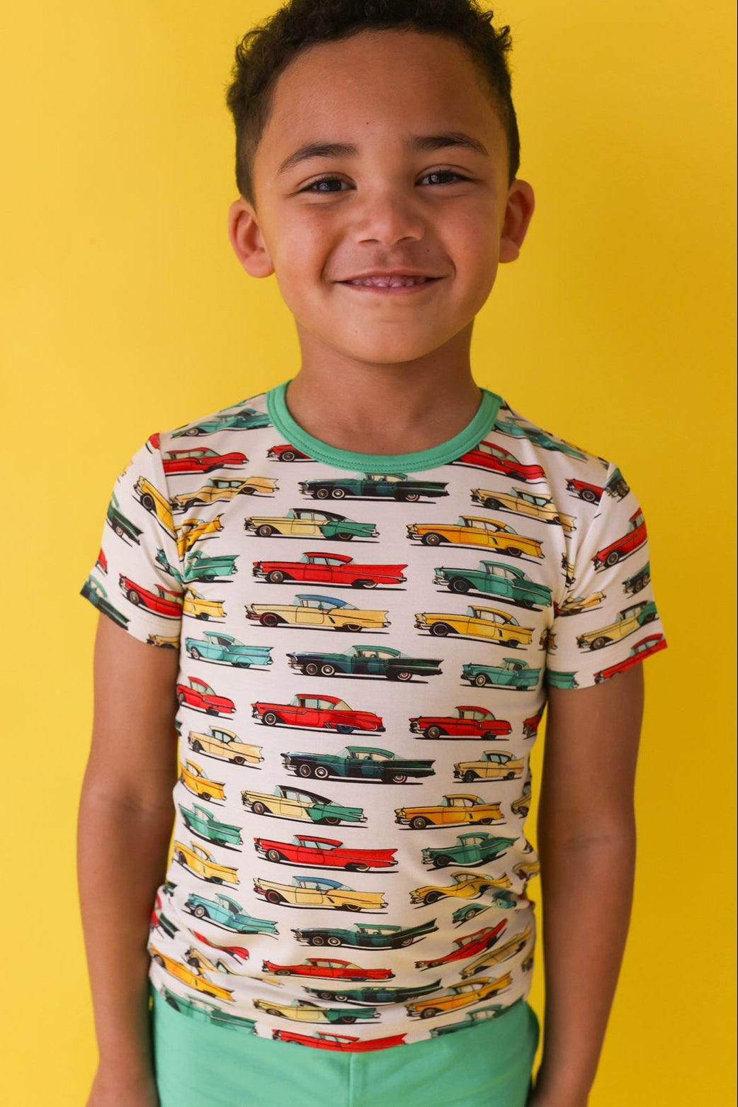 Close-up of retro classic cars graphic on kids’ short sleeve t-shirt, worn by a little boy — soft bamboo blend and vibrant colors.