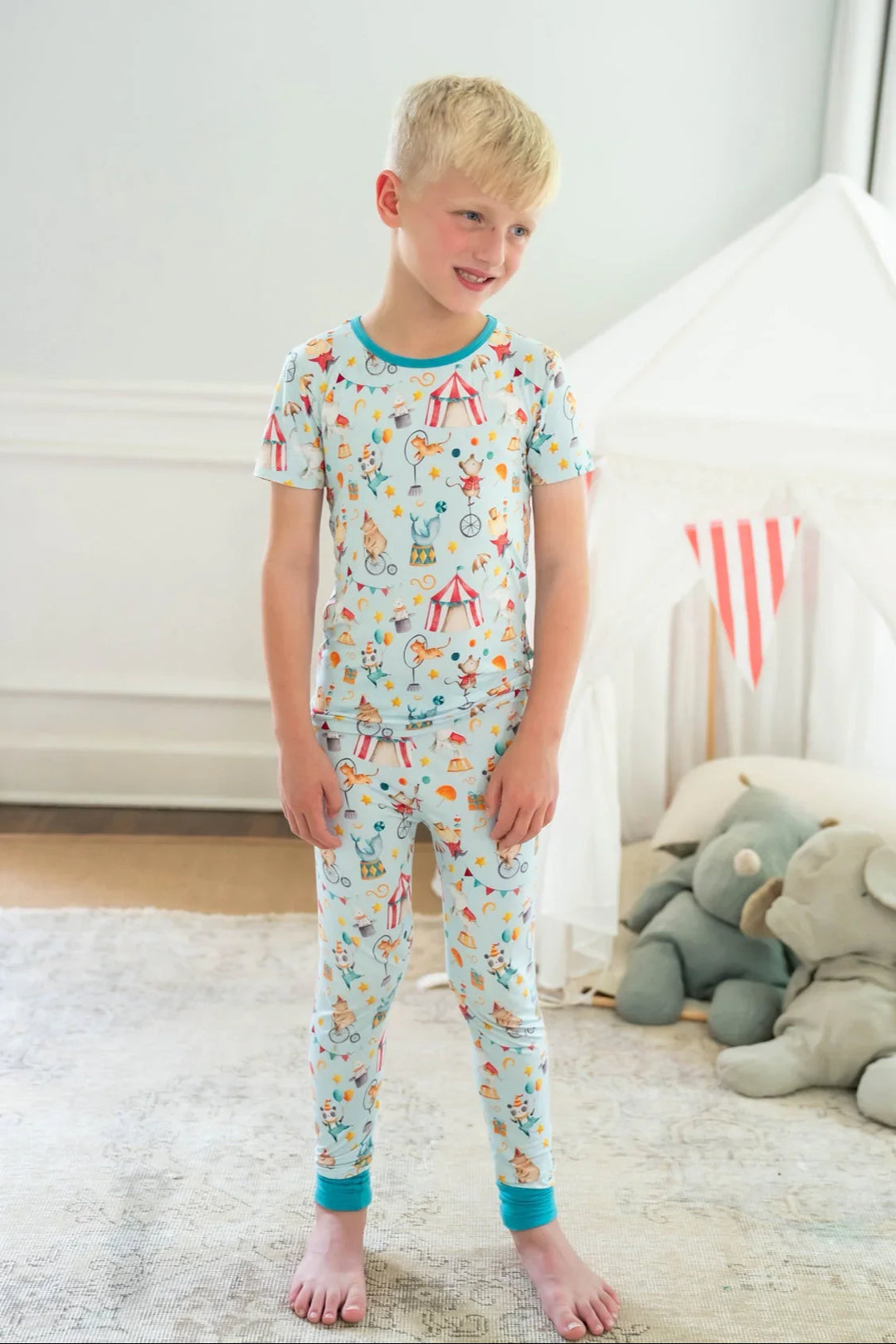 Little boy in front-facing view wearing Take Me to the Circus bamboo pajamas with short sleeves and long pants.