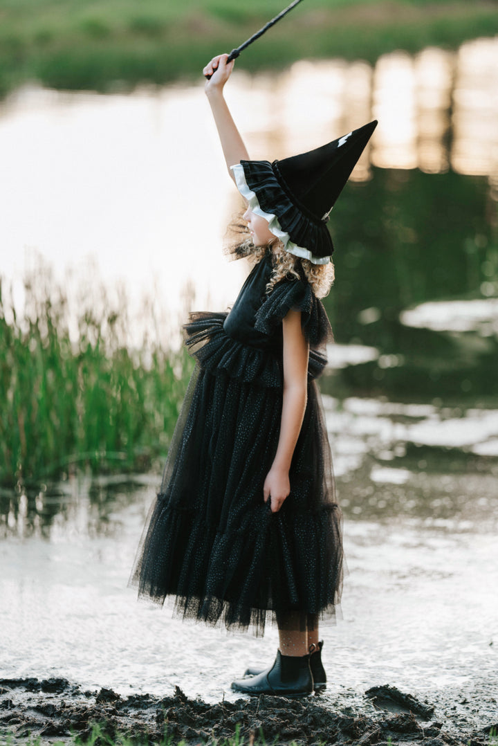 Side view of sparkly black tulle witch dress for girls Halloween costume holding wand