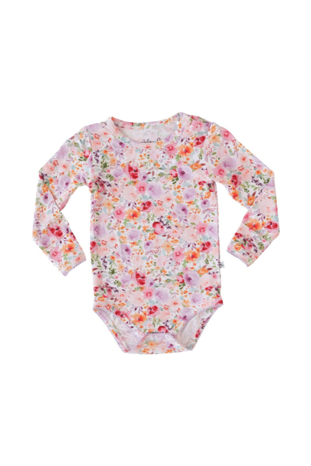 Flat lay of long sleeve bamboo baby bodysuit in flower garden print with scalloped edging and snap bottom closure.