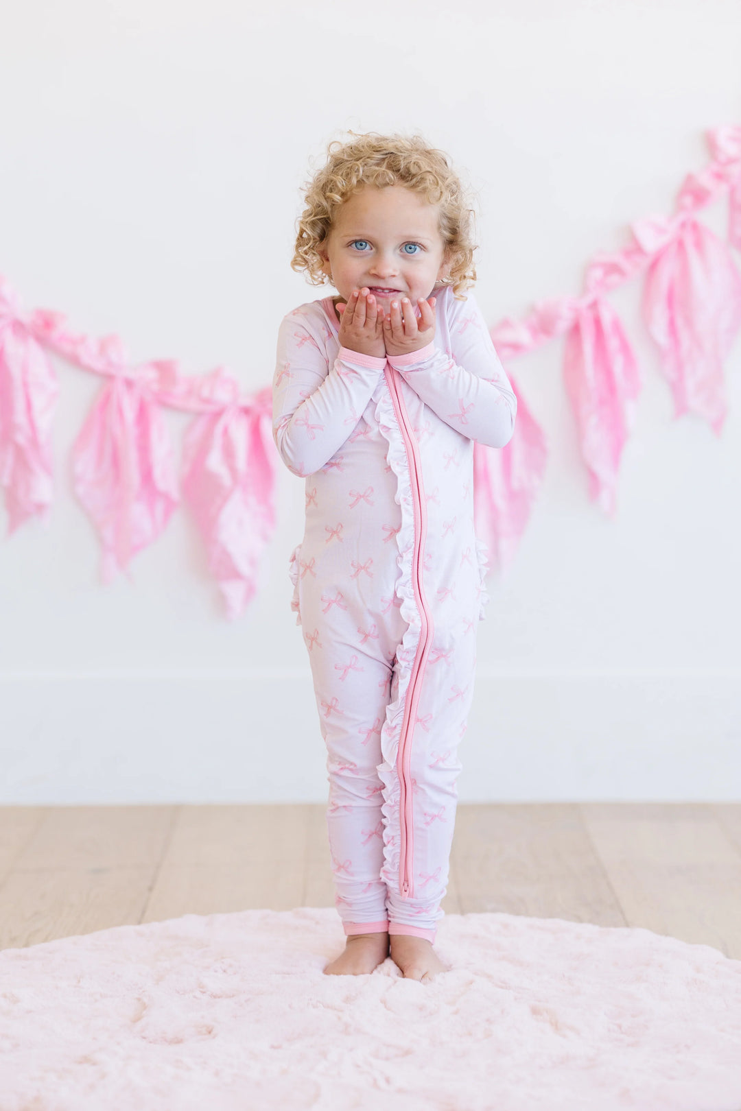 Front view of toddler in pink bows bamboo zipper pajamas, long sleeves with convertible feet and dual zipper.
