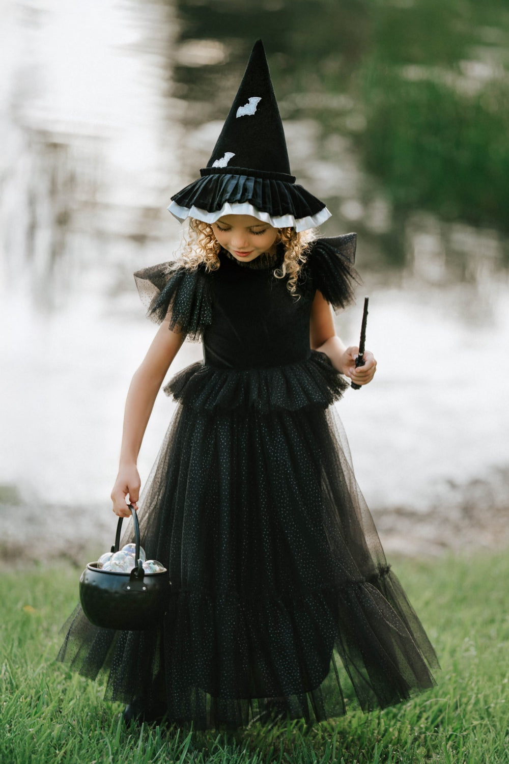 Child wearing whimsical velvet witch dress twirling with glitter wand
