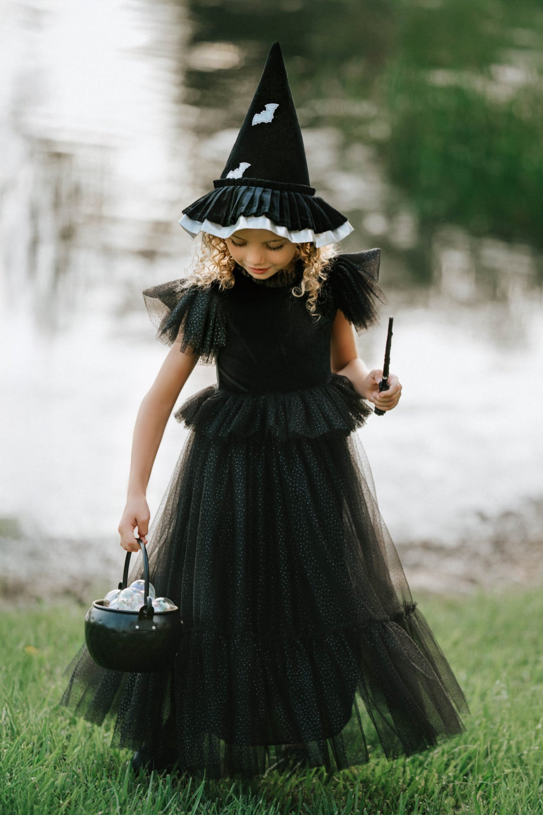 Child wearing whimsical velvet witch dress twirling with glitter wand