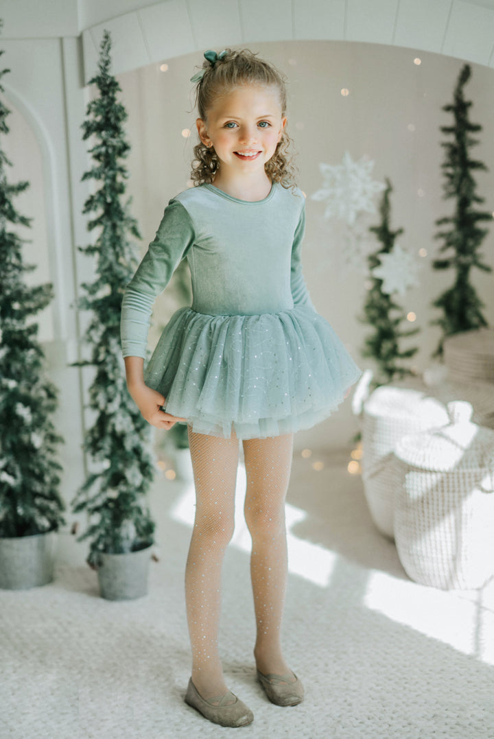 Girl wearing Willow green long sleeve tutu dress in winter evergreen setting.