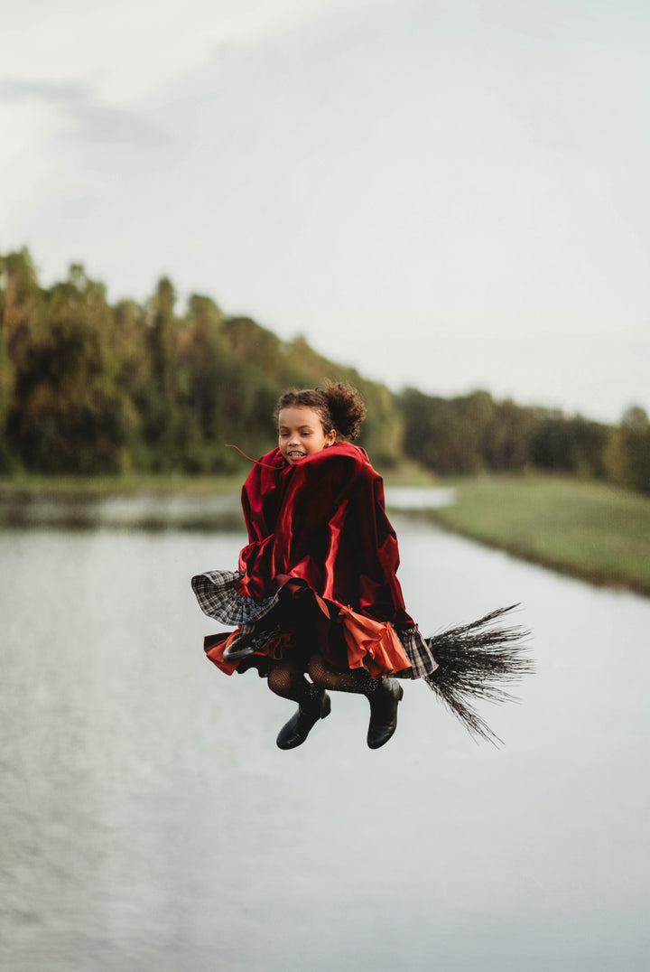 Child flying on broomstick in Hocus Pocus witch costume – Mary Sanderson inspired red cape
