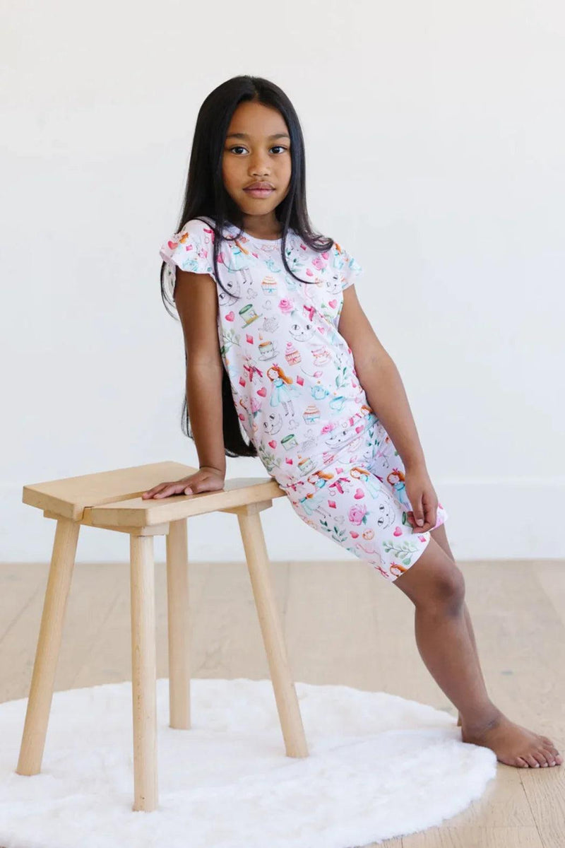 Front view of child in pink Adventures with Alice bamboo short sleeve pajamas, featuring soft stretch fabric and whimsical print.
