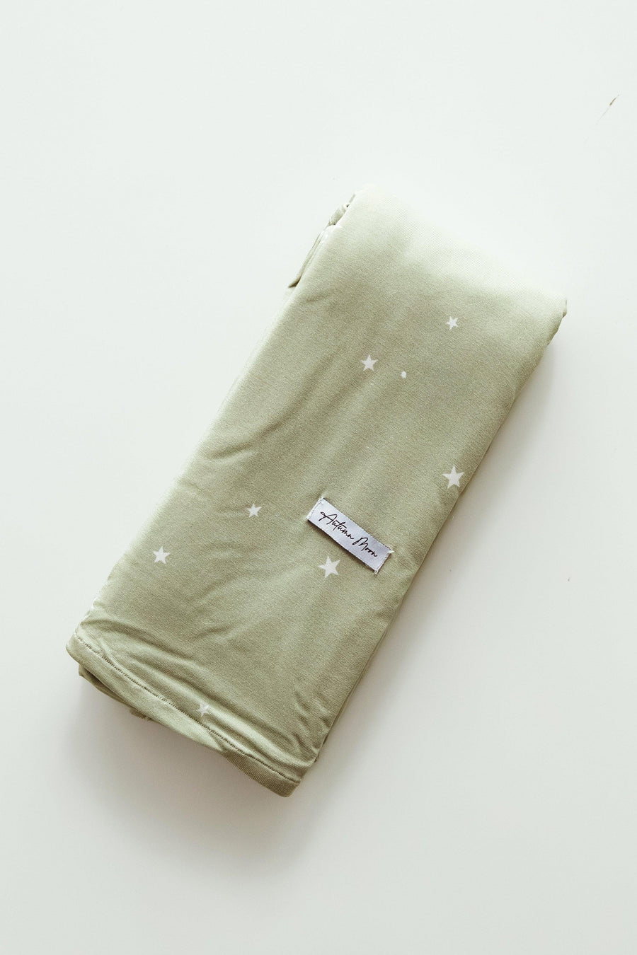Flat lay of sage green bamboo swaddle blanket with off-white scattered star print, made of ultra-soft, breathable bamboo viscose — perfect for newborns, baby showers, and gender-neutral nurseries.
