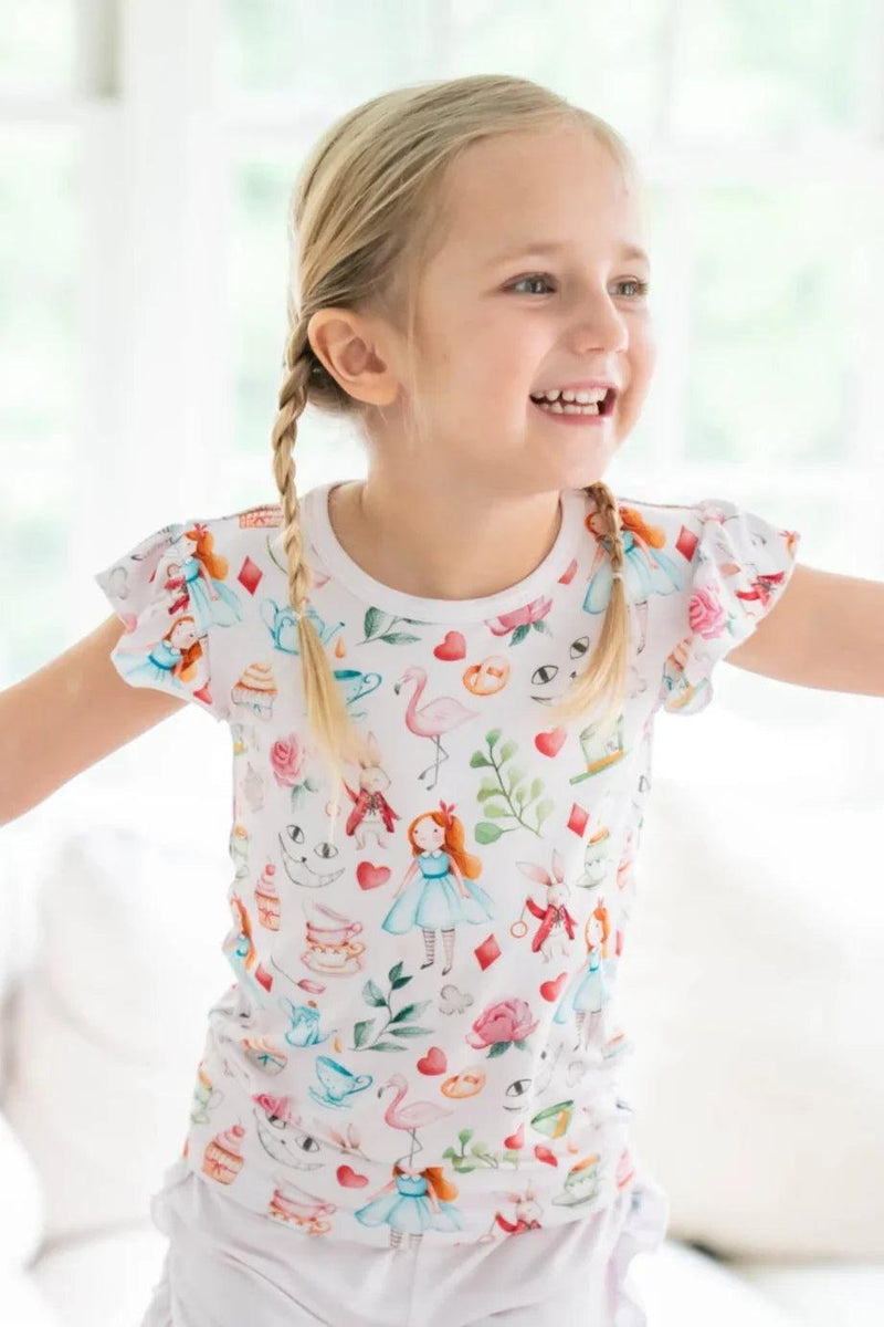 Girl wearing Adventures with Alice bamboo T-shirt, short ruffle sleeves and pink Alice in Wonderland print, front view.