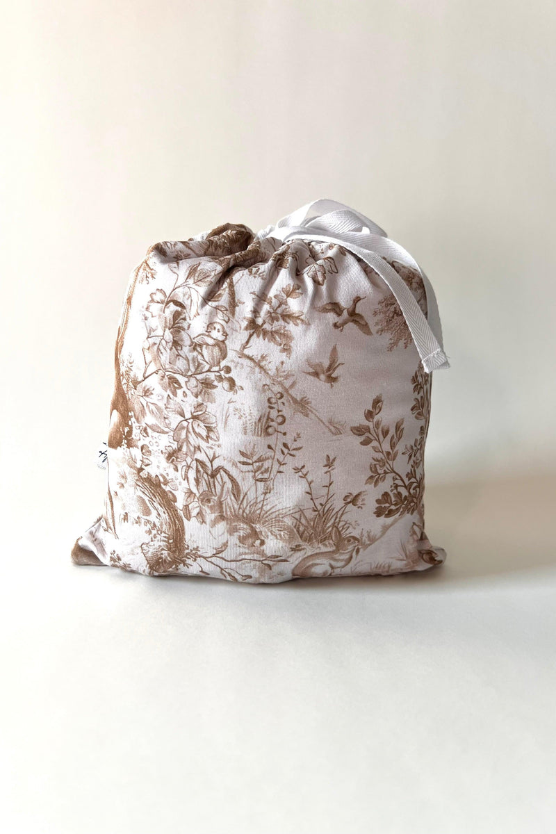 Woodland Toile bamboo crib sheet folded neatly in branded packaging, showcasing the brown and white unisex forest print — perfect for gifting or baby registry.
