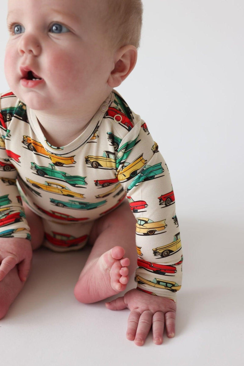 Baby sitting and smiling in classic cars long sleeve bamboo bodysuit with snap closure — cozy, stretchy outfit perfect for everyday wear or layering.
