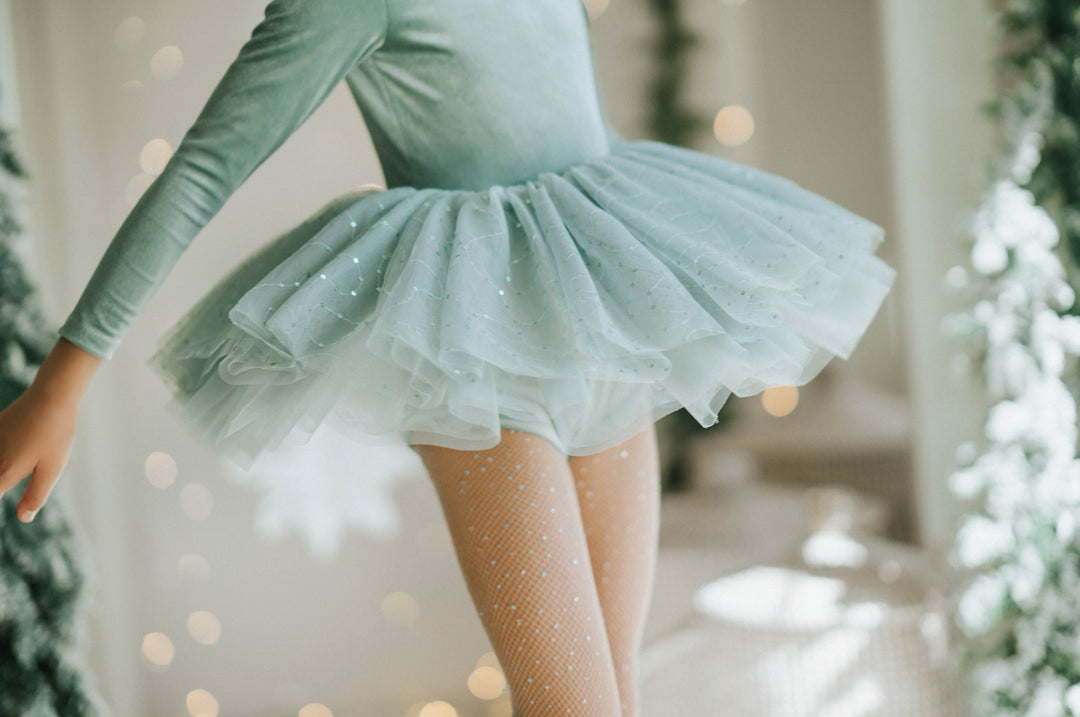 Girl spinning in Willow sparkle tutu dress with evergreen trees in background.