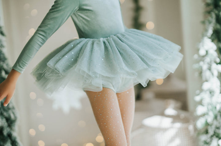 Girl spinning in Willow sparkle tutu dress with evergreen trees in background.