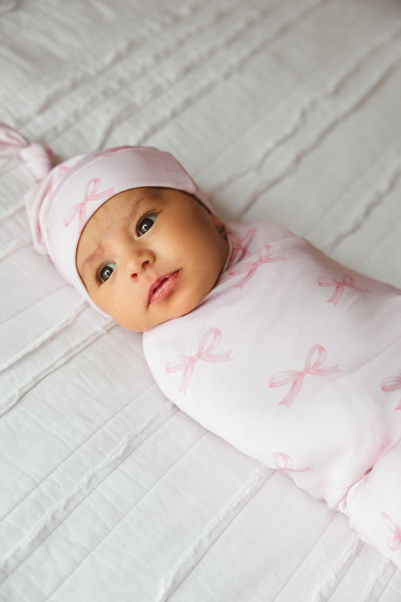 Newborn baby girl wrapped in Pink Bows bamboo swaddle blanket with coordinating bow hat, peacefully resting in soft, breathable fabric — perfect for hospital photos, gifting, and baby girl essentials.