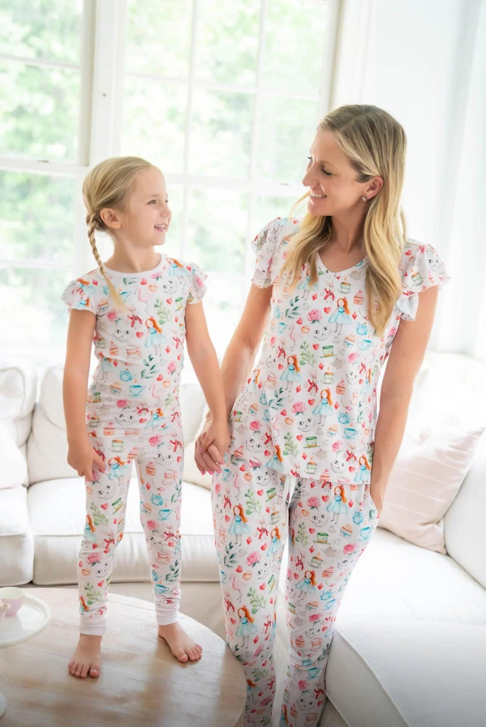 Parent and child wearing Adventures with Alice family matching pajamas, featuring playful pink Alice-themed print.