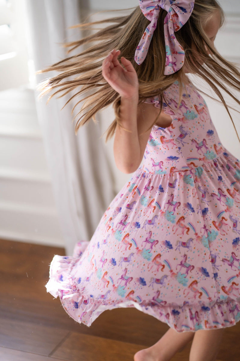 Magical Unicorns dress in motion as girl twirls in soft bamboo fabric, showing ruffle sleeve detail and dreamy unicorn pattern — designed for magical moments and all-day comfort.
