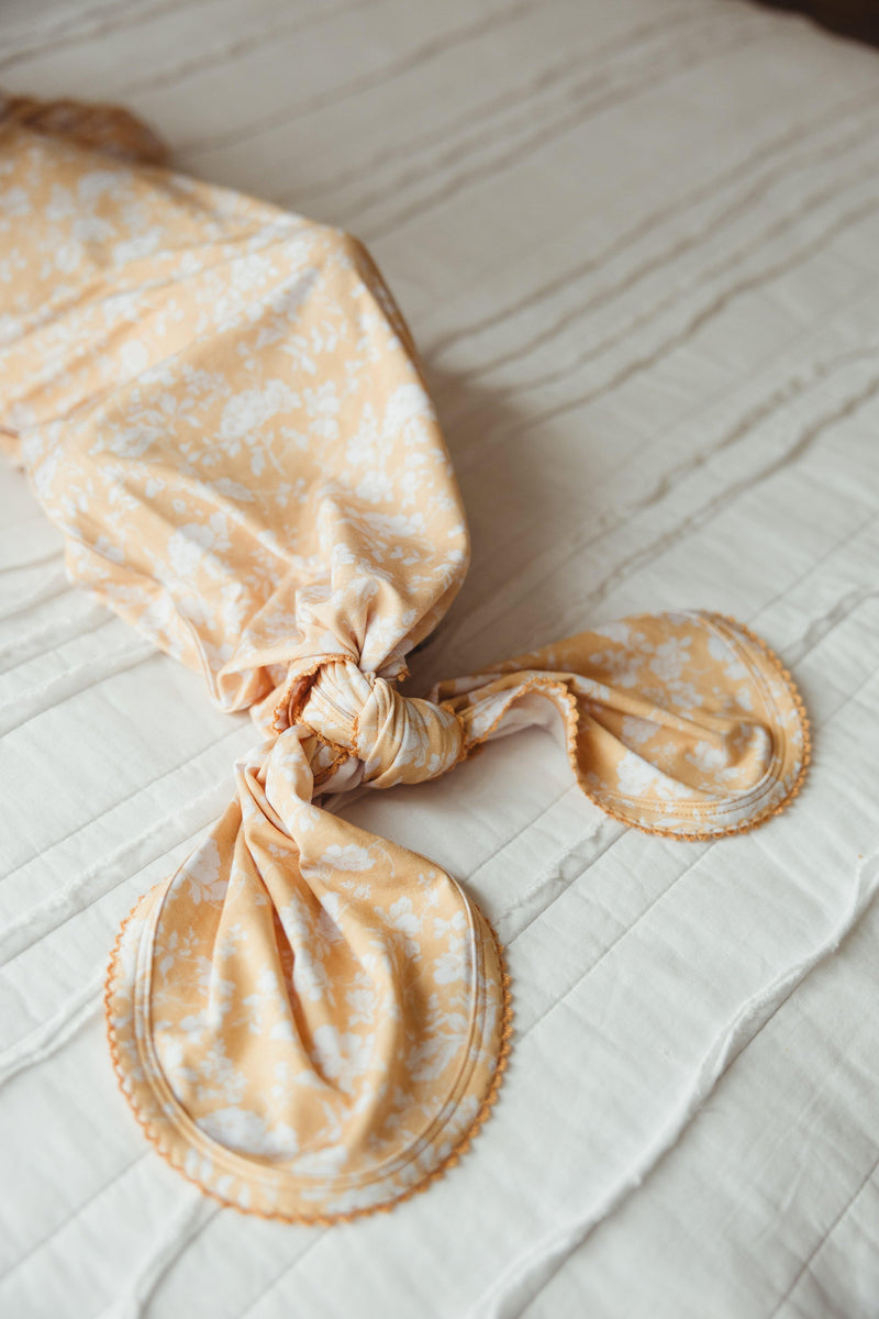 Close-up of knotted bottom on Golden Afternoon bamboo gown, showing scalloped trim and gentle stretch — easy for diaper changes and ideal for eco-friendly baby shower gifts.
