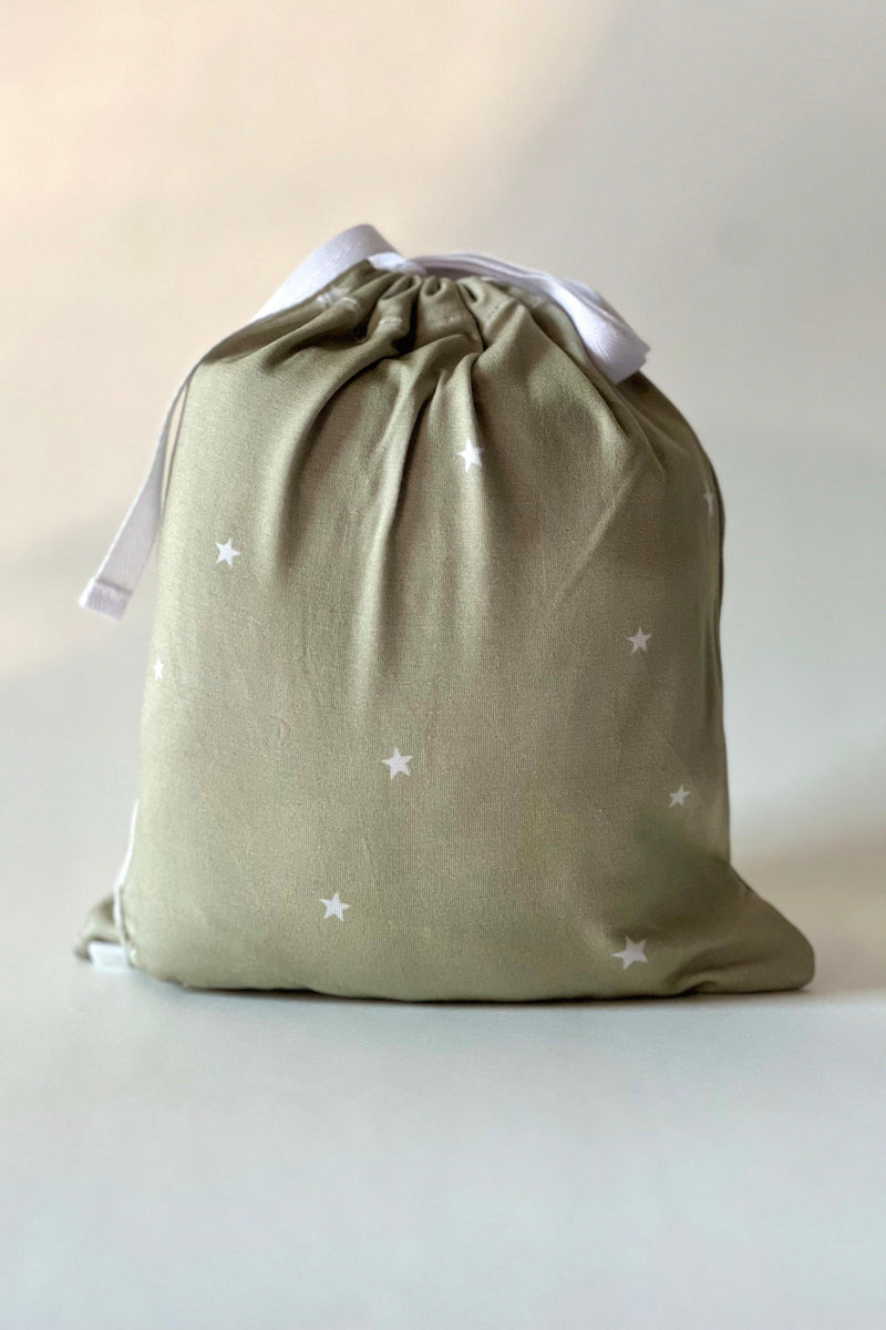 Sage stars bamboo crib sheet folded inside matching drawstring pouch with label — eco-friendly, gift-ready packaging ideal for baby showers and registries.
