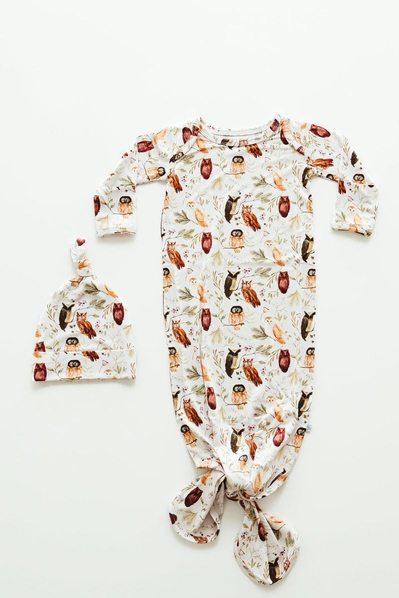 Flat lay of Sleepy Hollow Owls bamboo newborn knotted gown, featuring a soft cream background with baby owls perched on branches — cozy, breathable, and perfect for natural woodland-themed nurseries.