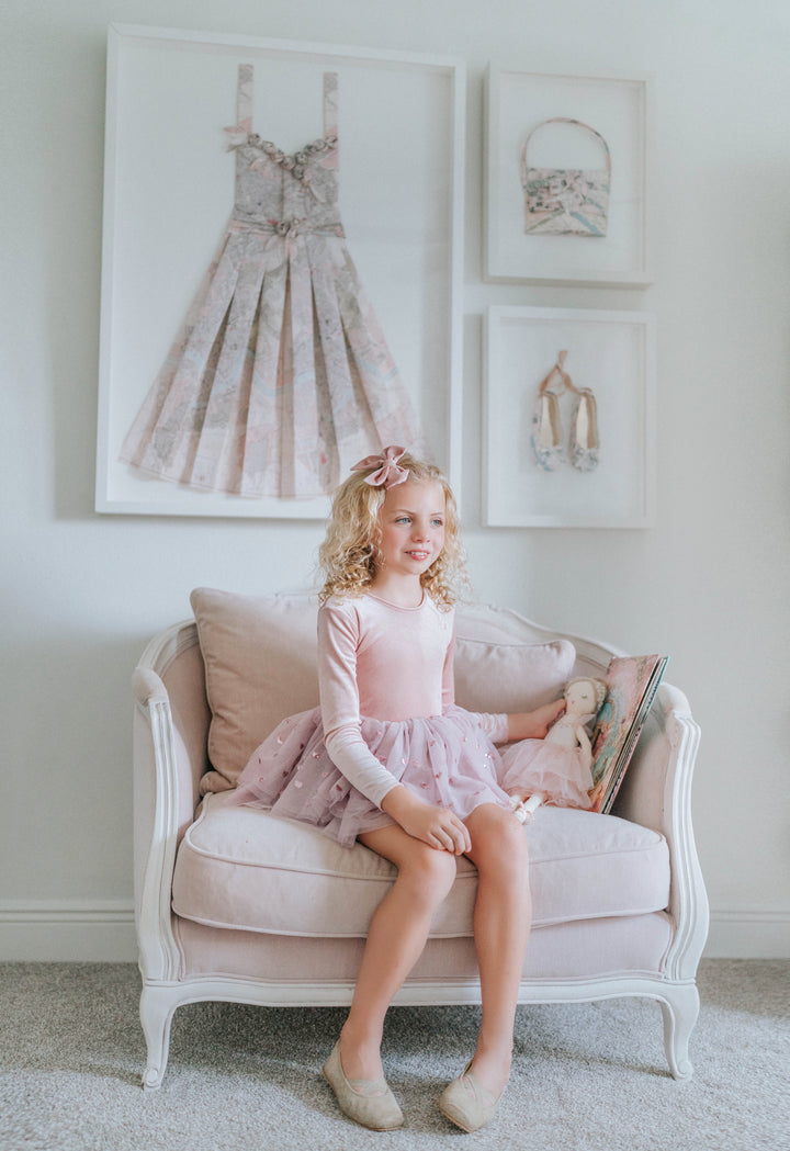 Girl seated in soft French-inspired chair wearing rosewood heart tulle tutu dress.