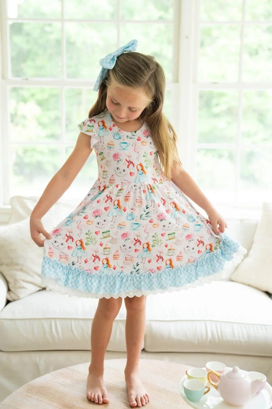 Girl twirling in Adventures with Alice bamboo twirl dress featuring short ruffle sleeves, gingham ruffle, and eyelet lace trim.