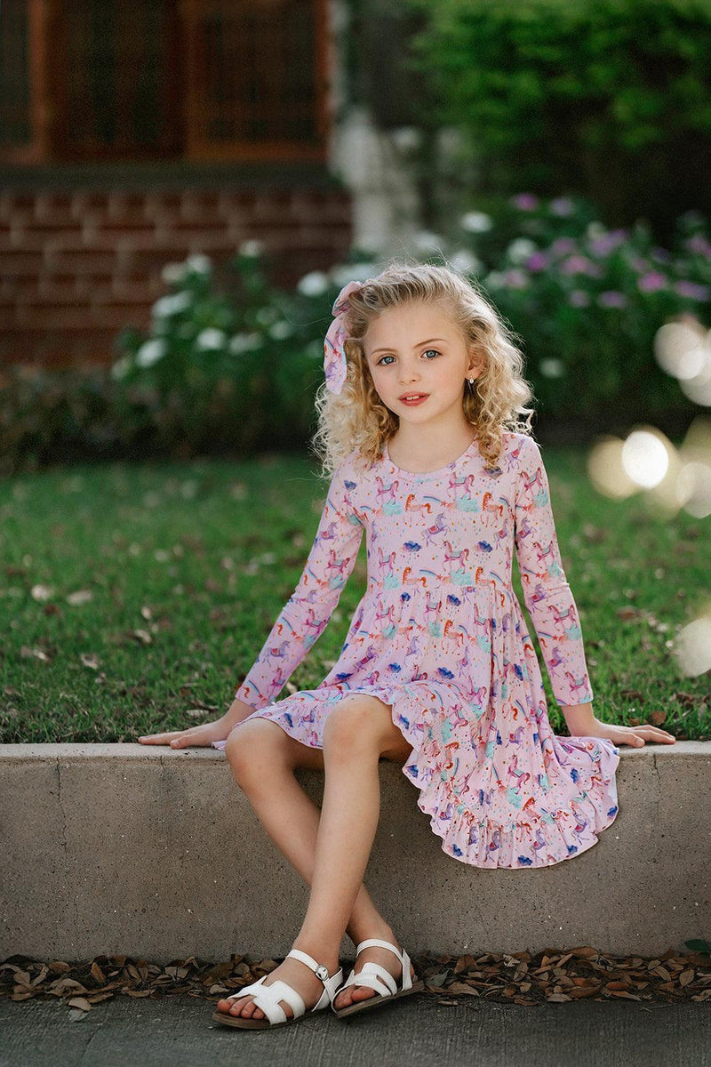 Front view of girl in pastel unicorn twirl dress with long sleeves and ruffled skirt — made from buttery soft bamboo fabric, ideal for sensitive skin and everyday magic.
