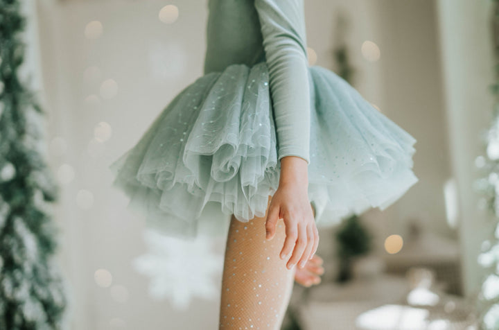 Girl spinning in Willow sparkle tutu dress with evergreen trees in background.