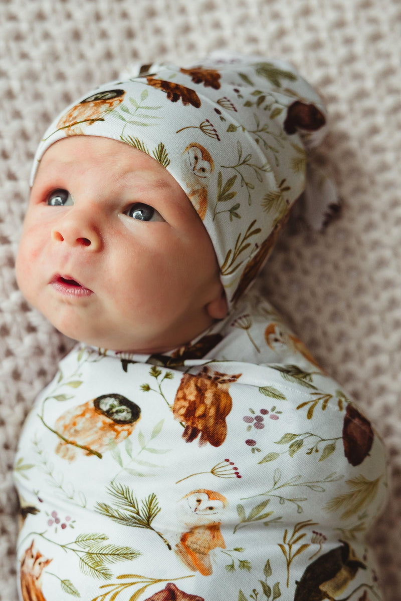 Newborn baby boy wrapped in Sleepy Hollow Owls bamboo swaddle blanket and matching hat, peacefully resting in buttery soft, breathable fabric — cozy and calming for first photos or gifting.
