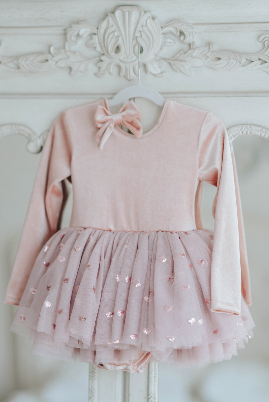 Rosewood velvet tutu dress styled with matching bow accessory, displayed on hanger.