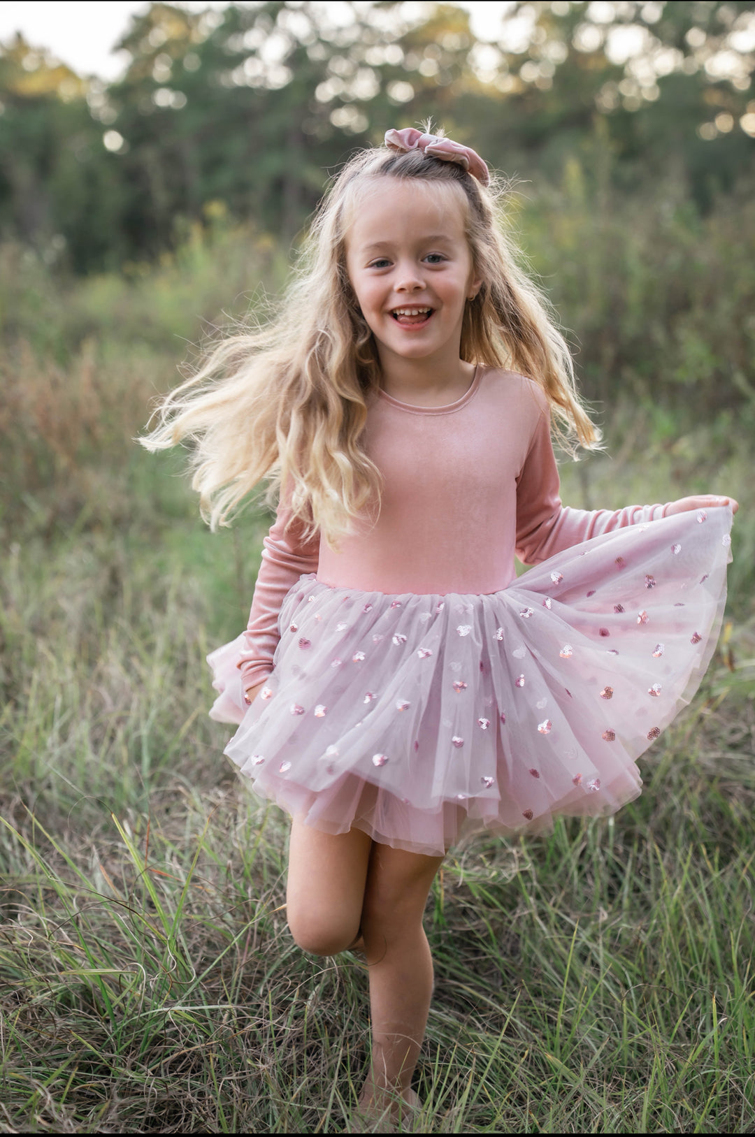 Girl spinning outdoors in rosewood velvet tutu dress with layered pink heart tulle skirt.