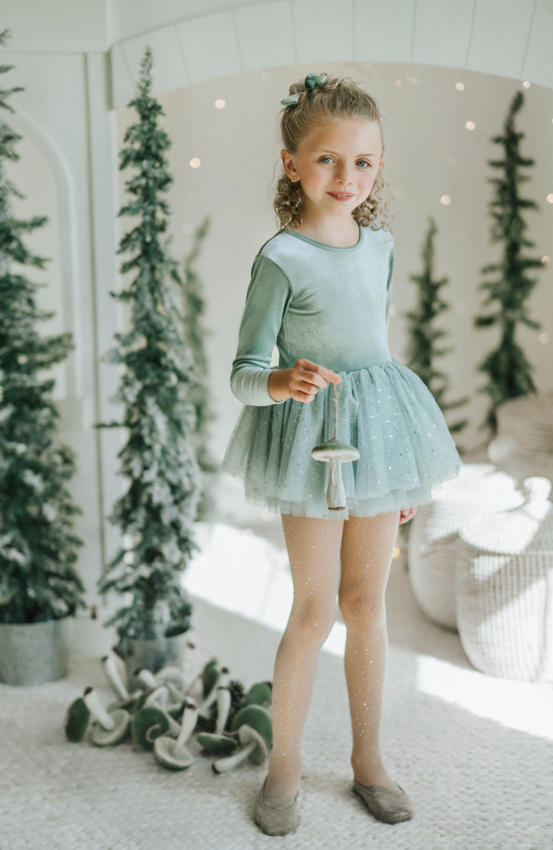 Portrait of girl wearing Willow tutu dress styled for winter holiday photo with mushroom ornament .