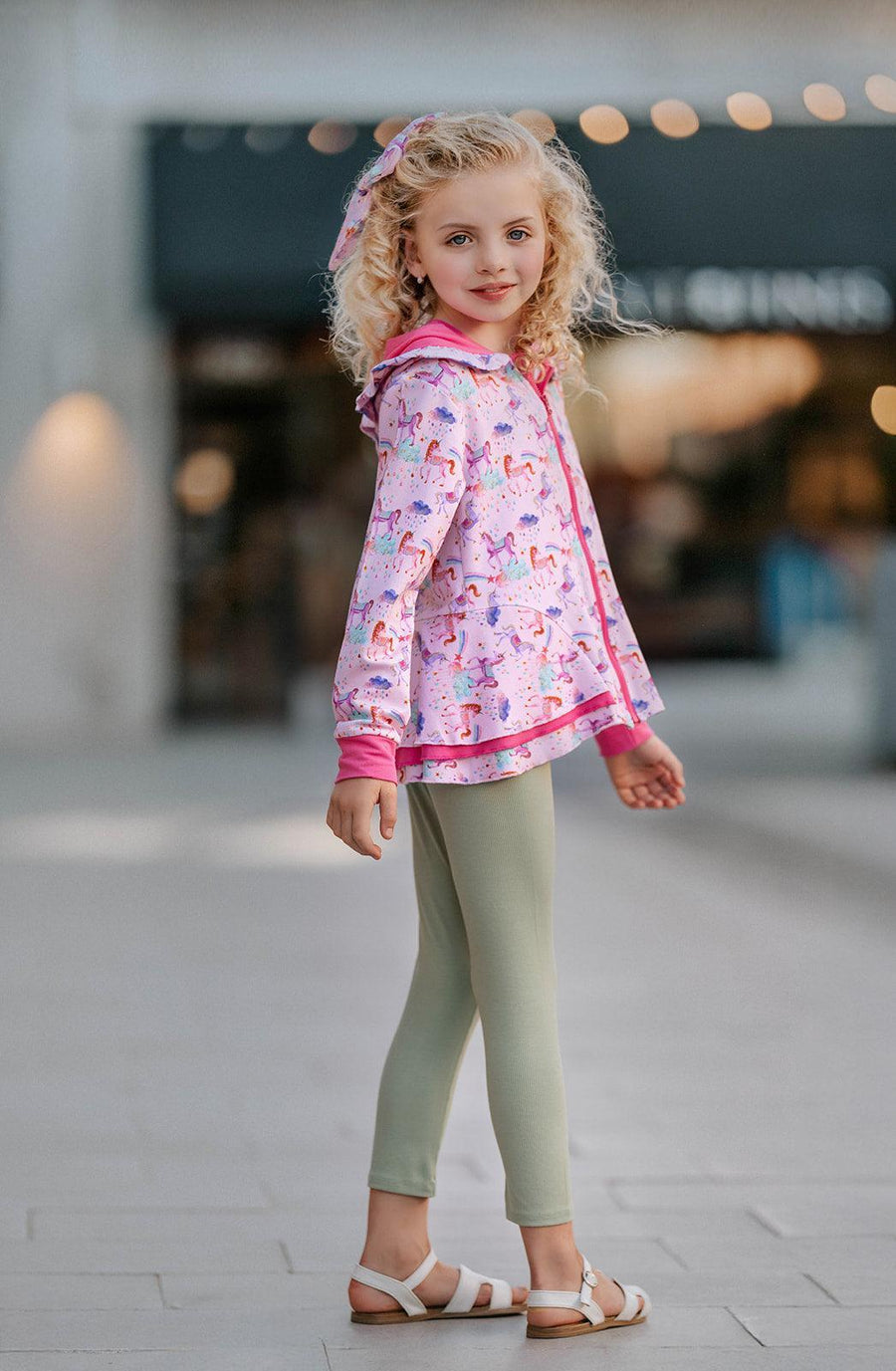 Back view of girl walking in Magical Unicorns bamboo zipper jacket, highlighting double ruffle peplum layers and unicorn print — feminine and playful, perfect for layering in cooler weather.