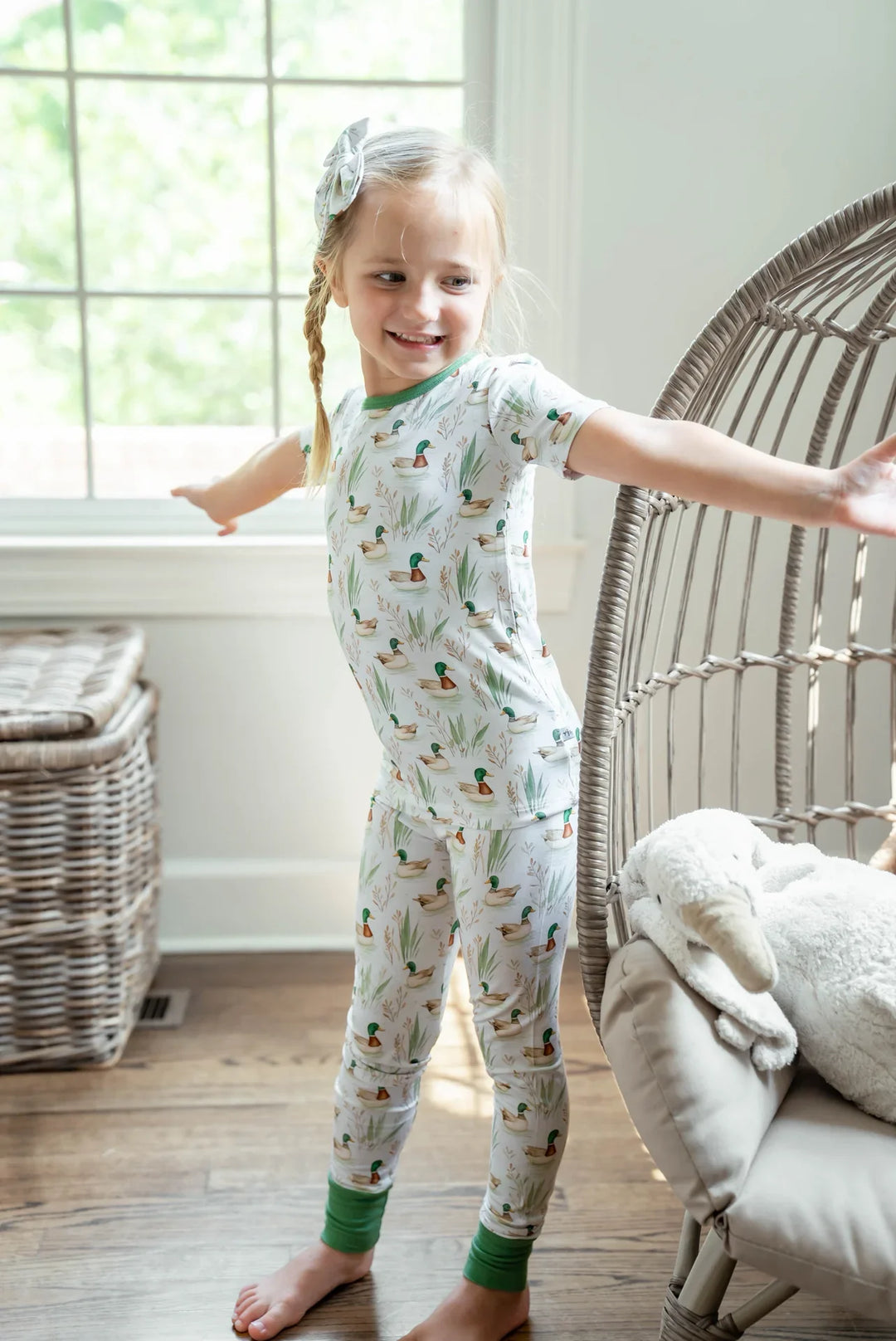 Little girl sitting in mallard duck two-piece bamboo pajamas, cozy and soft for bedtime or lounging.