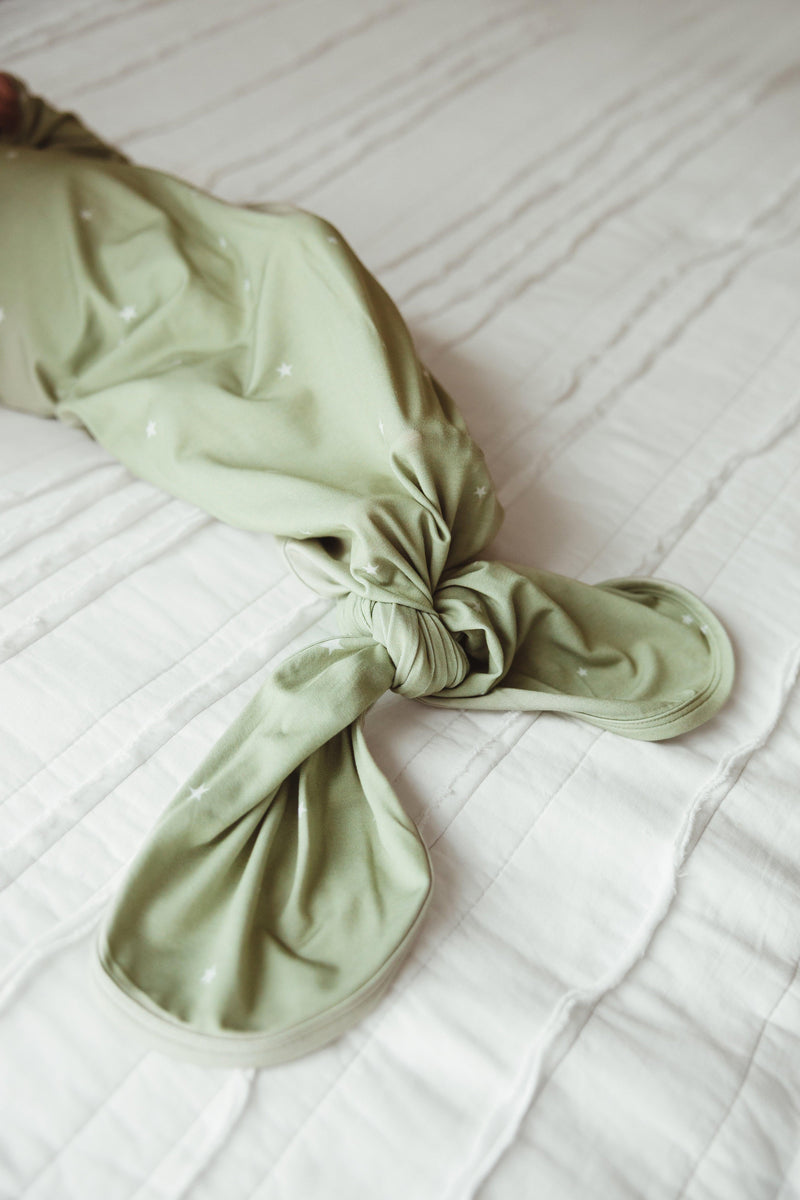 Close-up of adjustable knotted bottom on sage green bamboo newborn gown with off-white stars, highlighting soft stretch and easy diaper access.
