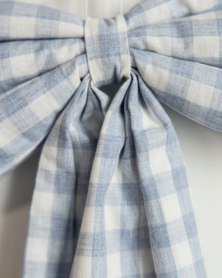 Close-up of handcrafted baby blue gingham fabric bow with classic cotton detailing.