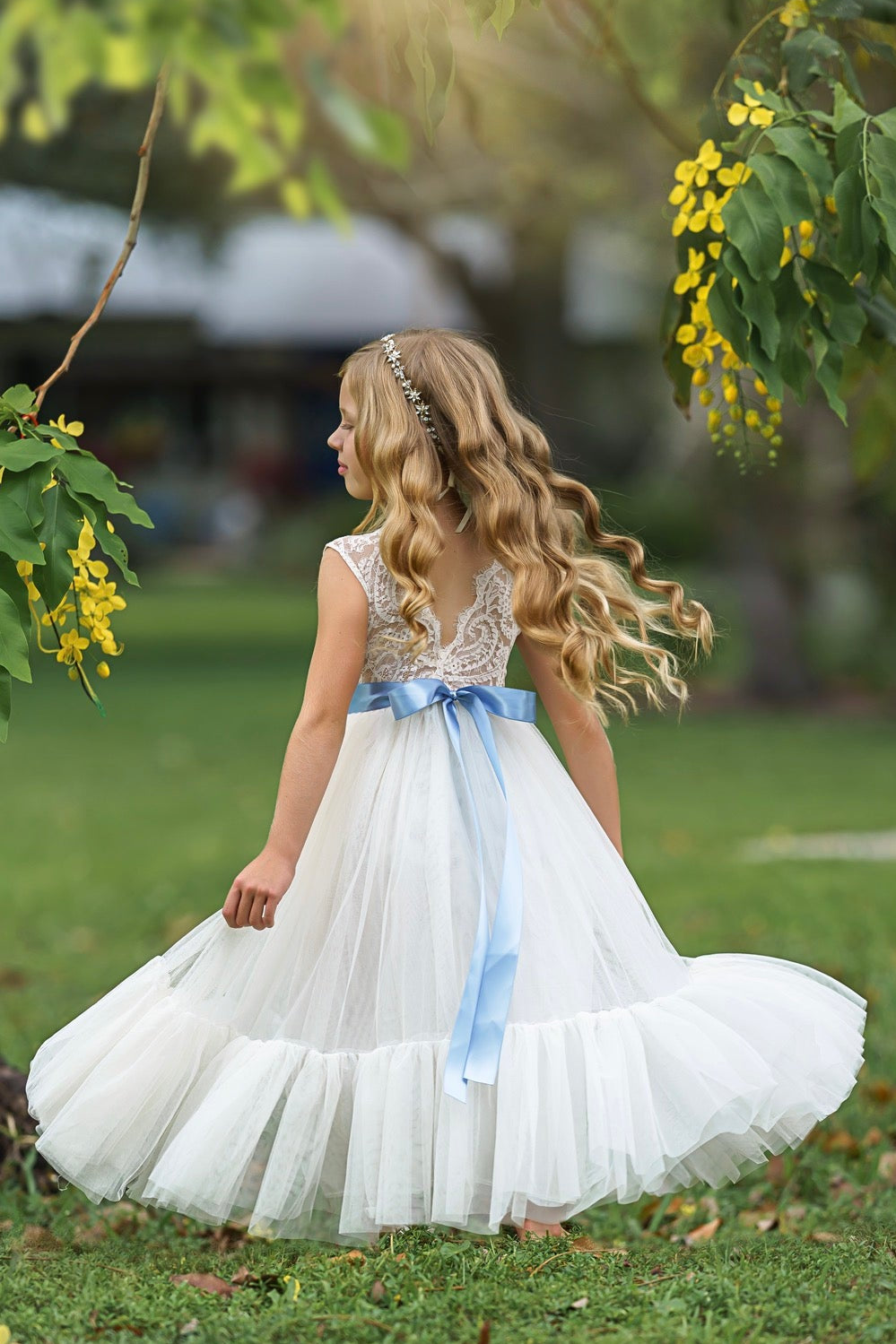 Back view of antique ivory flower girl gown showing eyelash lace V-back and long tulle skirt