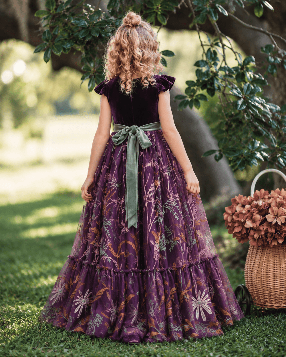 Back view of eggplant purple velvet flower girl dress with sage green bow sash