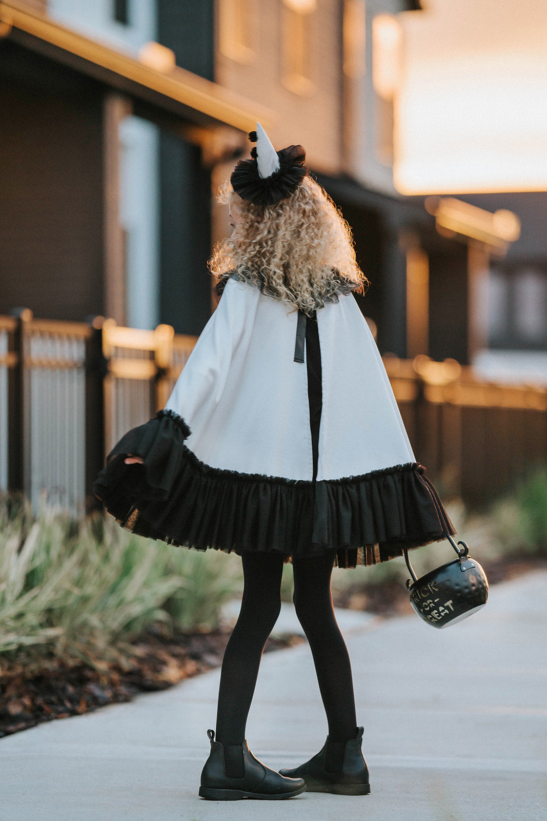 Back view of the white satin Pirouette clown cape showing the flowing satin construction and contrasting black tulle ruffle trim.