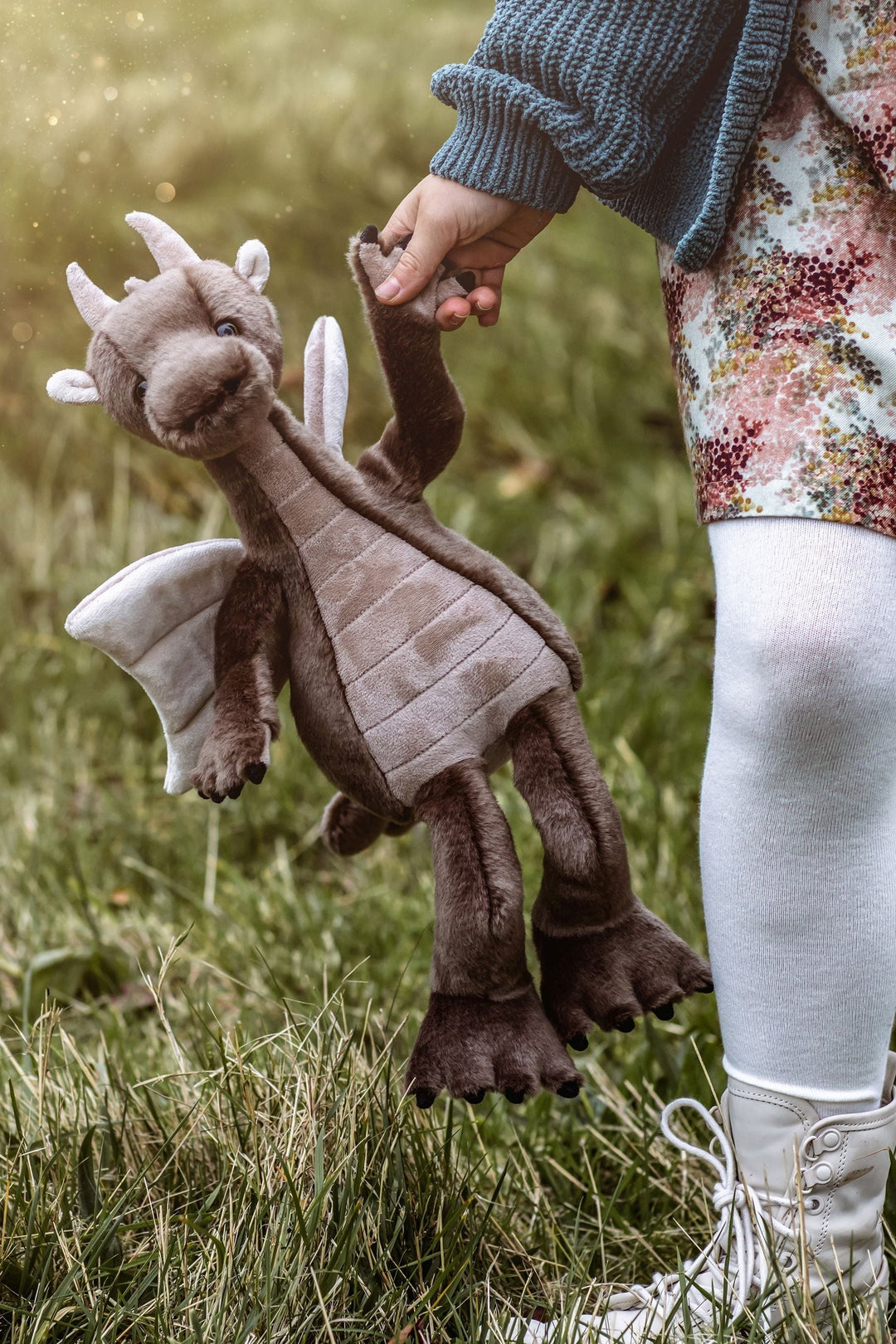 Clubs dragon plush by Charlie Bears being held outdoors in a grassy field