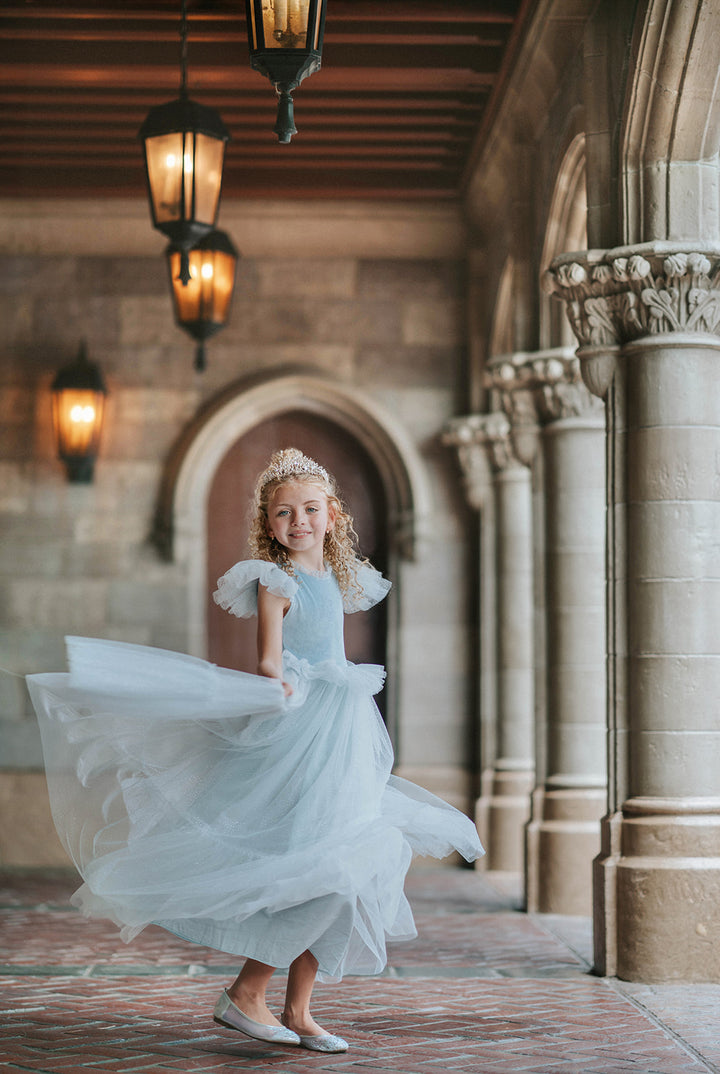 Girl twirling in blue velvet princess dress with layered sparkle tulle skirt