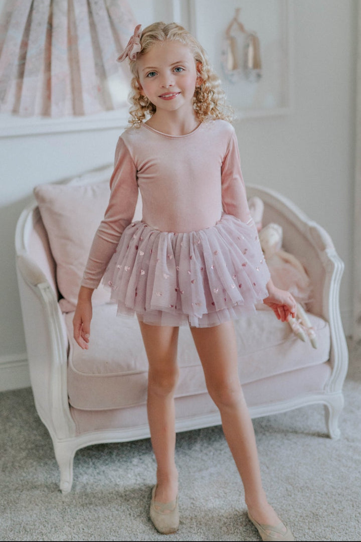 Girl standing in a soft neutral room wearing a rosewood velvet tutu dress with heart sequin tulle skirt.