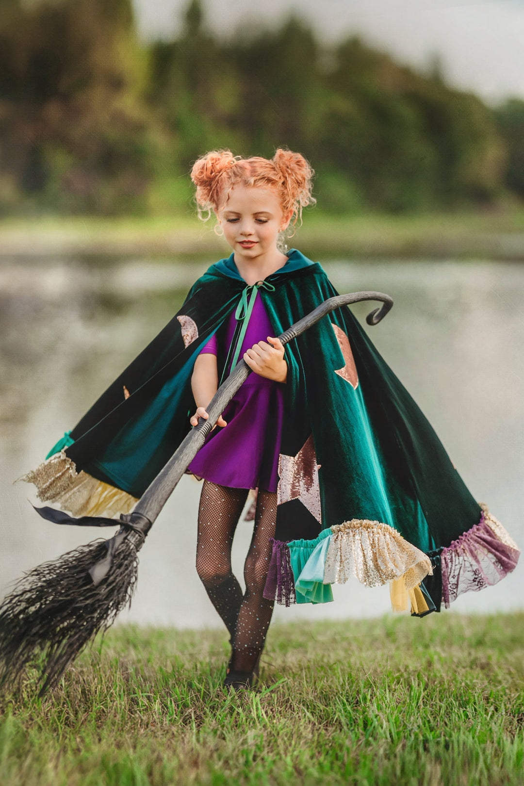 Child holding wand in green Winifred inspired witch cape with tie closure.