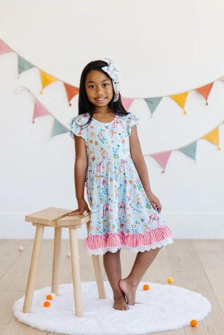 Little girl standing in Take Me to the Circus bamboo ruffle twirl dress, front view of short sleeve fit.