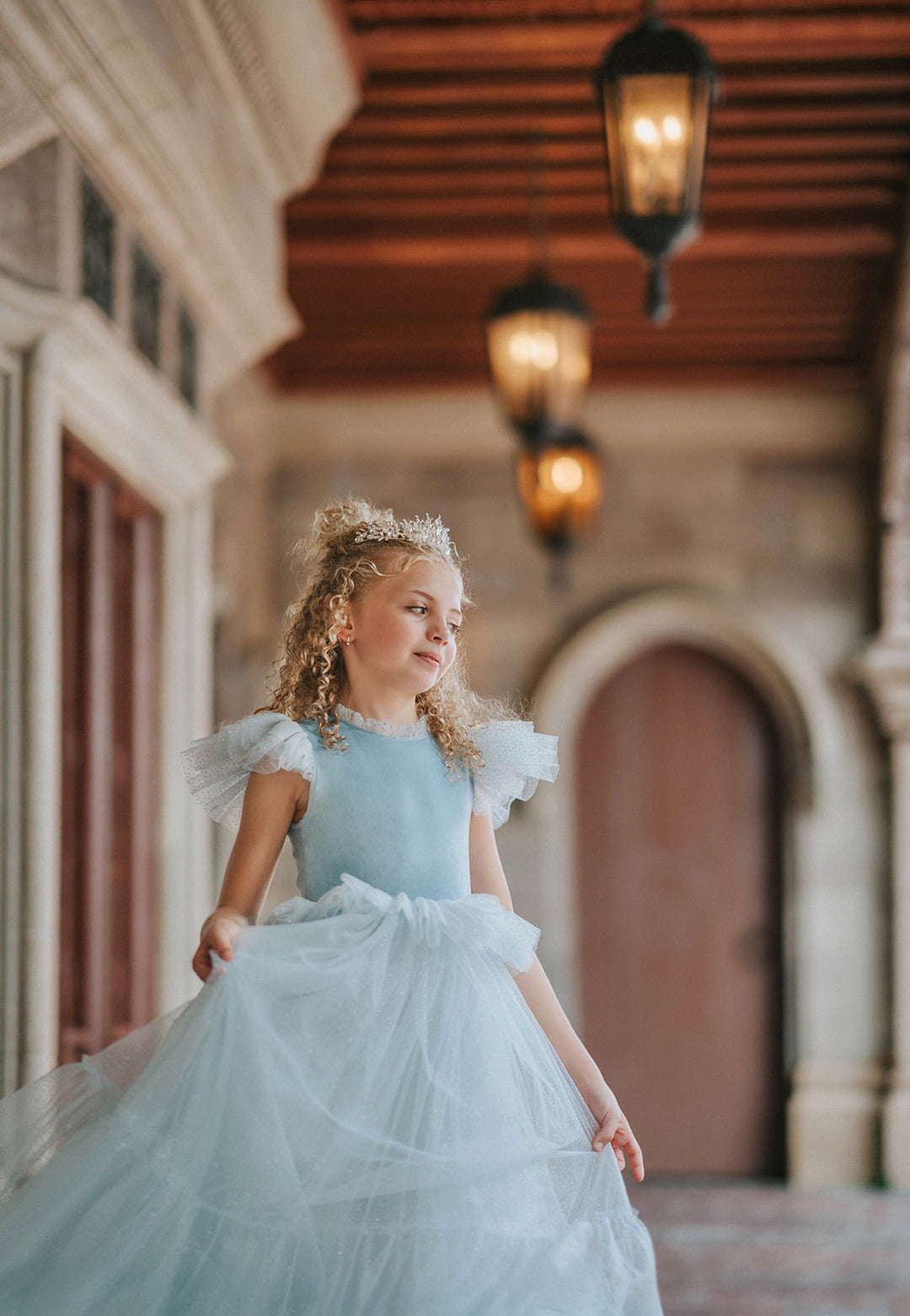 Girl wearing blue velvet and sparkle tulle princess dress in fairytale setting